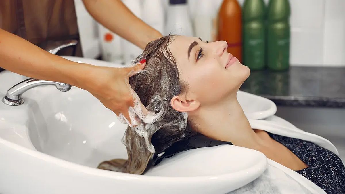 Hình ảnh một người phụ nữ đang gội đầu tại salon tóc.